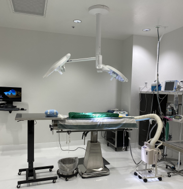 This is a photo of a clean, well-equipped surgical room at Civano: surgery table, lights, computer monitors and other equipment are present.