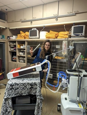 Dr. Tereza Stastny stands near a ventilation machine and a simulator and smiles.