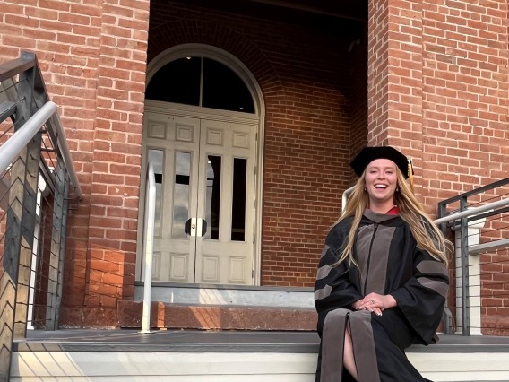 Caylee Childress poses in front of Old Main, a brick building.