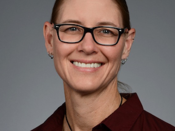 Picture of a woman with hair pulled back in a maroon blouse.