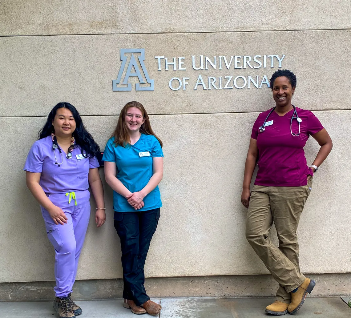 Students pose in front of the University of Arizona logo on a building at Reid Park Zoo.