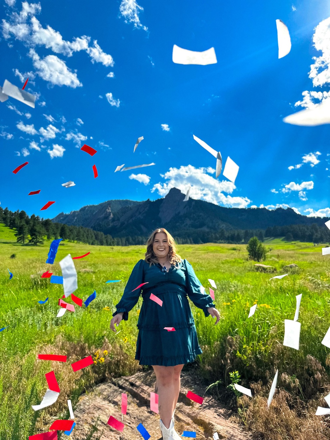 Student Haley McCarthy poses in front of a mountain landscape, and confetti flutters down around her.