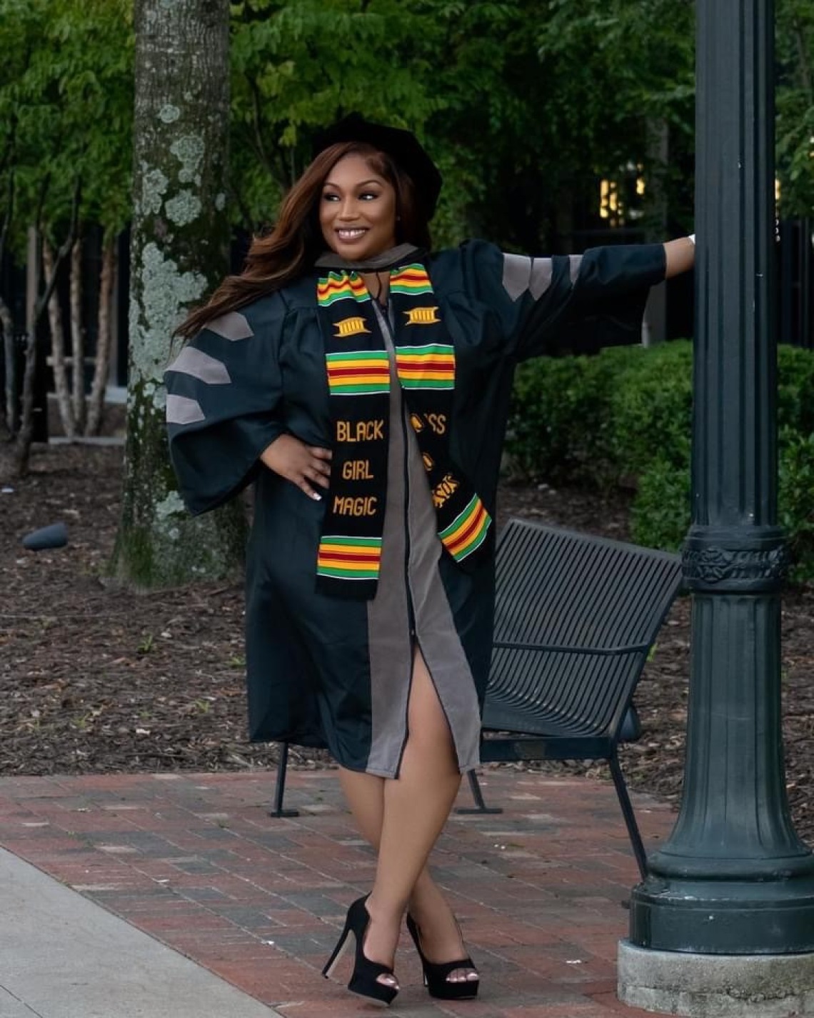 Brittany Johnson wears graduation regalia and poses in a park.
