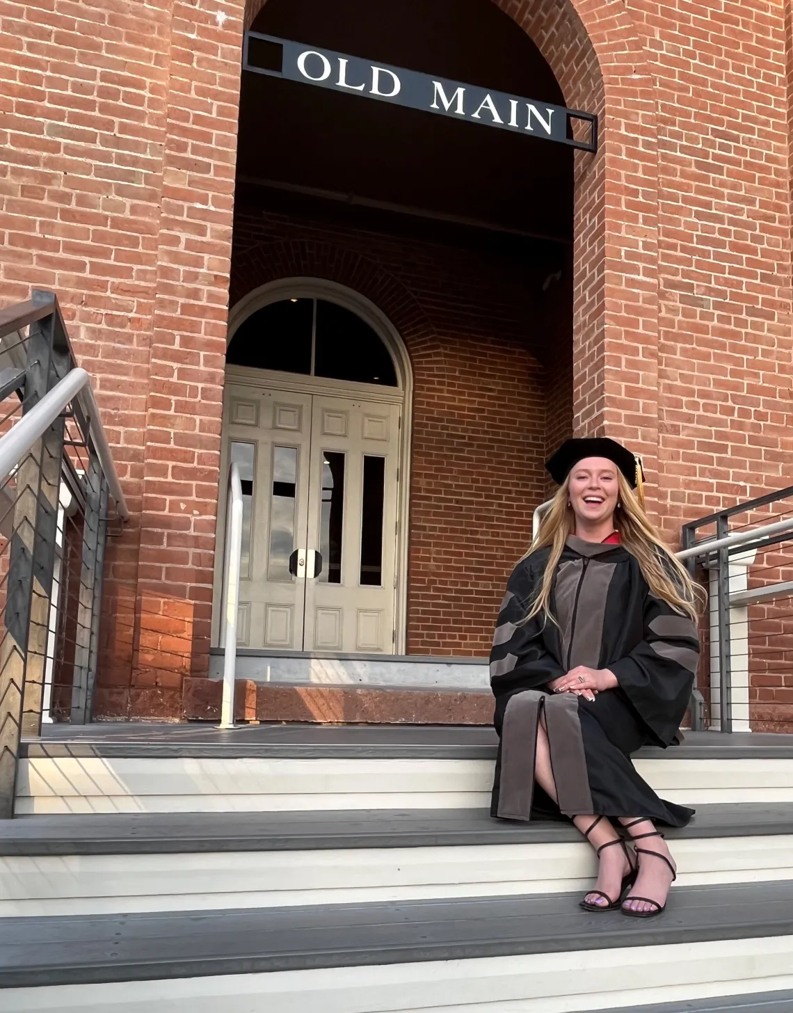 Caylee Childress poses in front of Old Main, a brick building.