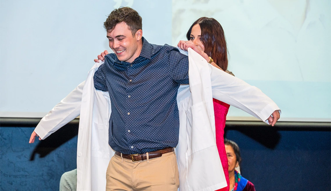 Student receiving white jacket during ceremony