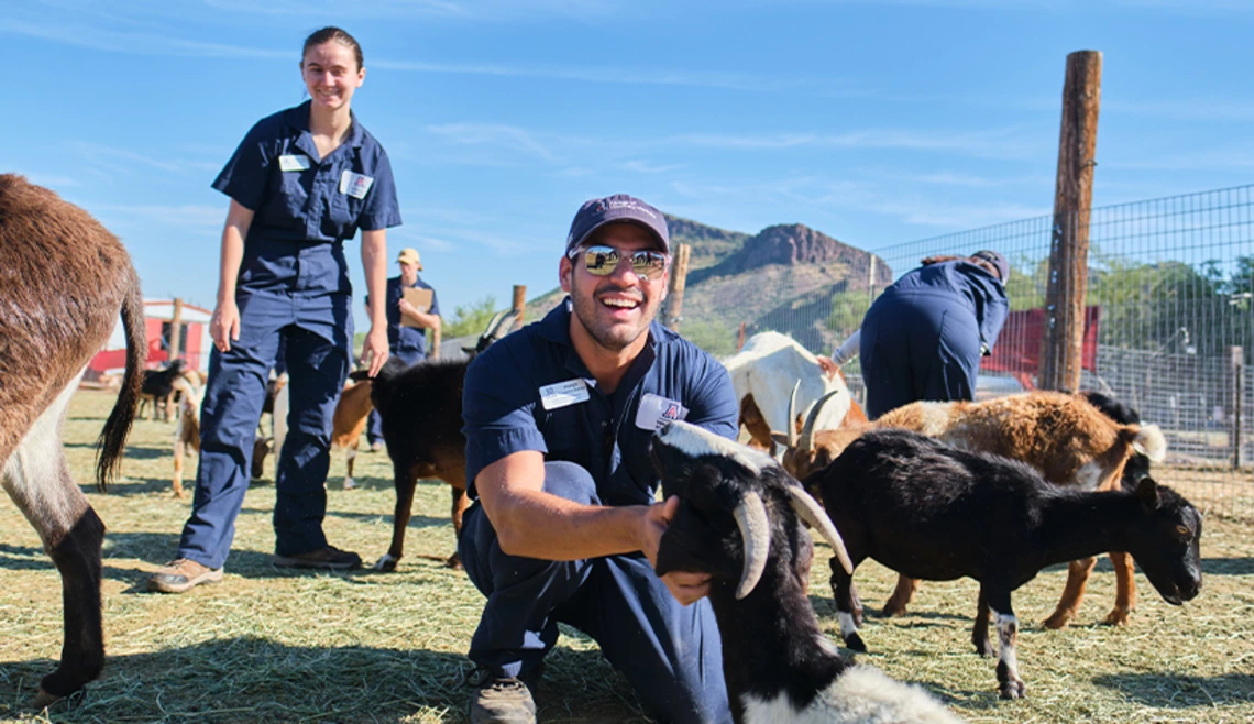 Student smiling and posing with goat