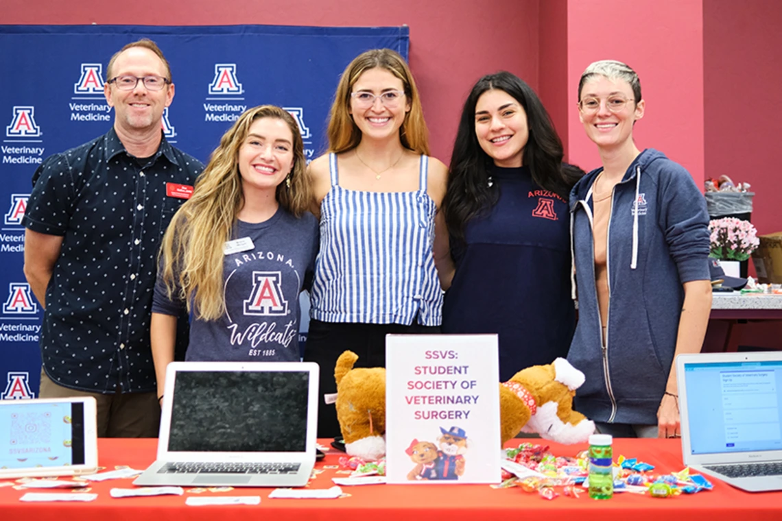 Group of students smiling and standing at university club table