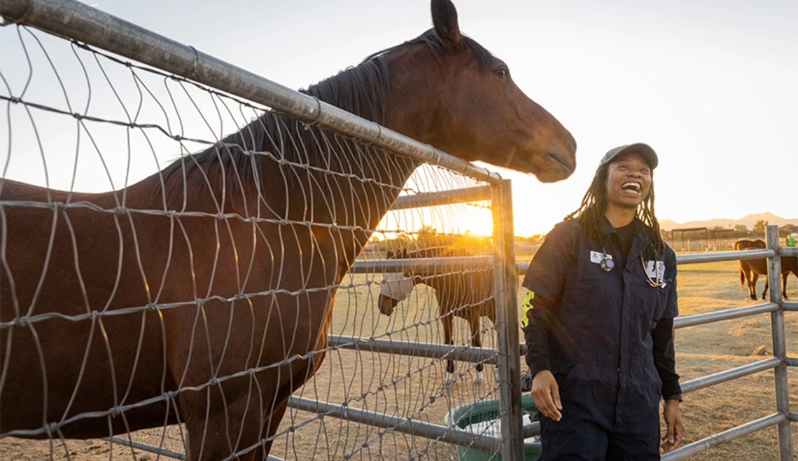 Student smiling while standing next to horse