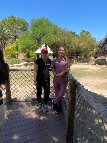 Two students stand on a platform outside at Reid Park Zoo.