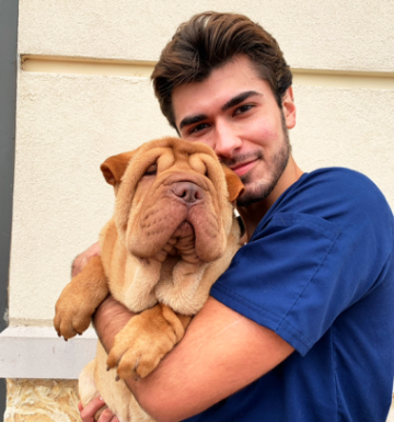 Ricky Wagner, a veterinary student, holds a Shar Pei dog.