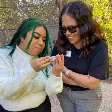 Two veterinary students examine a hummingbird nest in a small jar.