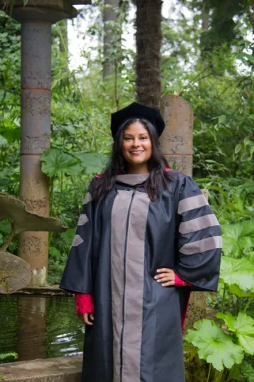 Evie Garcia stands outdoors in graduation regalia.