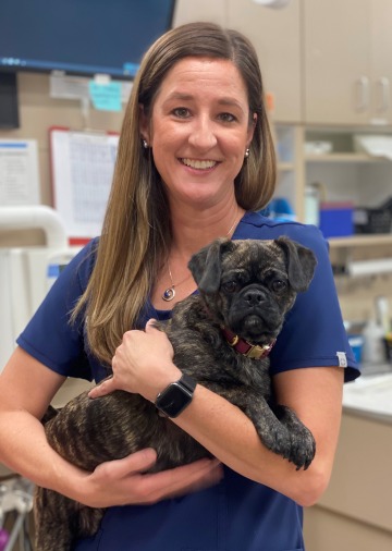 Dr. Kelli Evans holds a small brown pug.