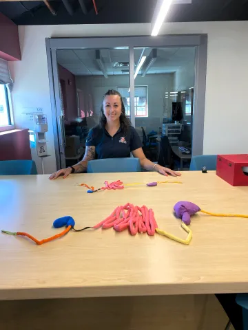 A woman poses in front of a portion of a fabric model of a bovine gastrointestinal tract.