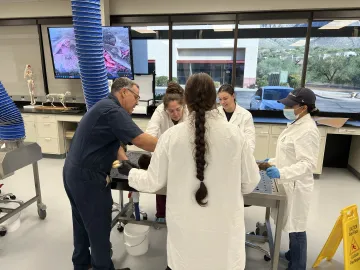 A professor and four students surround a table in a lab.