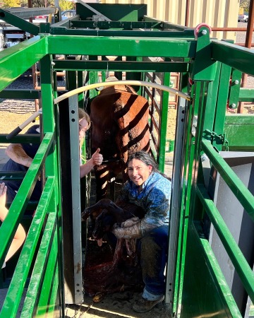 Hannah Bates stands next to a cattle chute and smiles.
