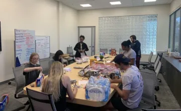 Club members sit around a large conference table to pack bags of food and water.