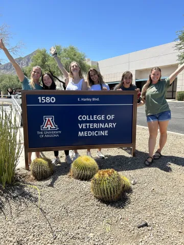 Sammy Kjelsberg with friends by the college of veterinary medicine sign