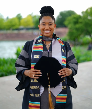 Danasia celebrating her graduation wearing regalia