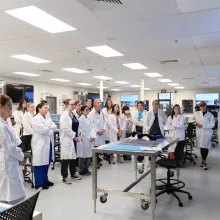 Students listening to a faculty member while in a lab. 