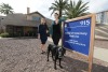 Dr. Maggie O'Haire and Sarah Leighton pose together in front of a sign that reads, "College of Veterinary Medicine Human-Animal Interaction House." The house, a research building, stands in the background.
